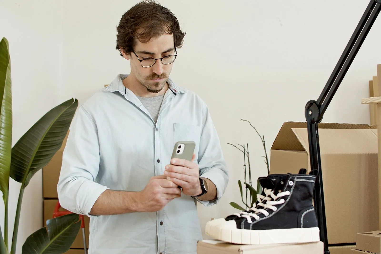A man photographing a pair of sneakers with his phone