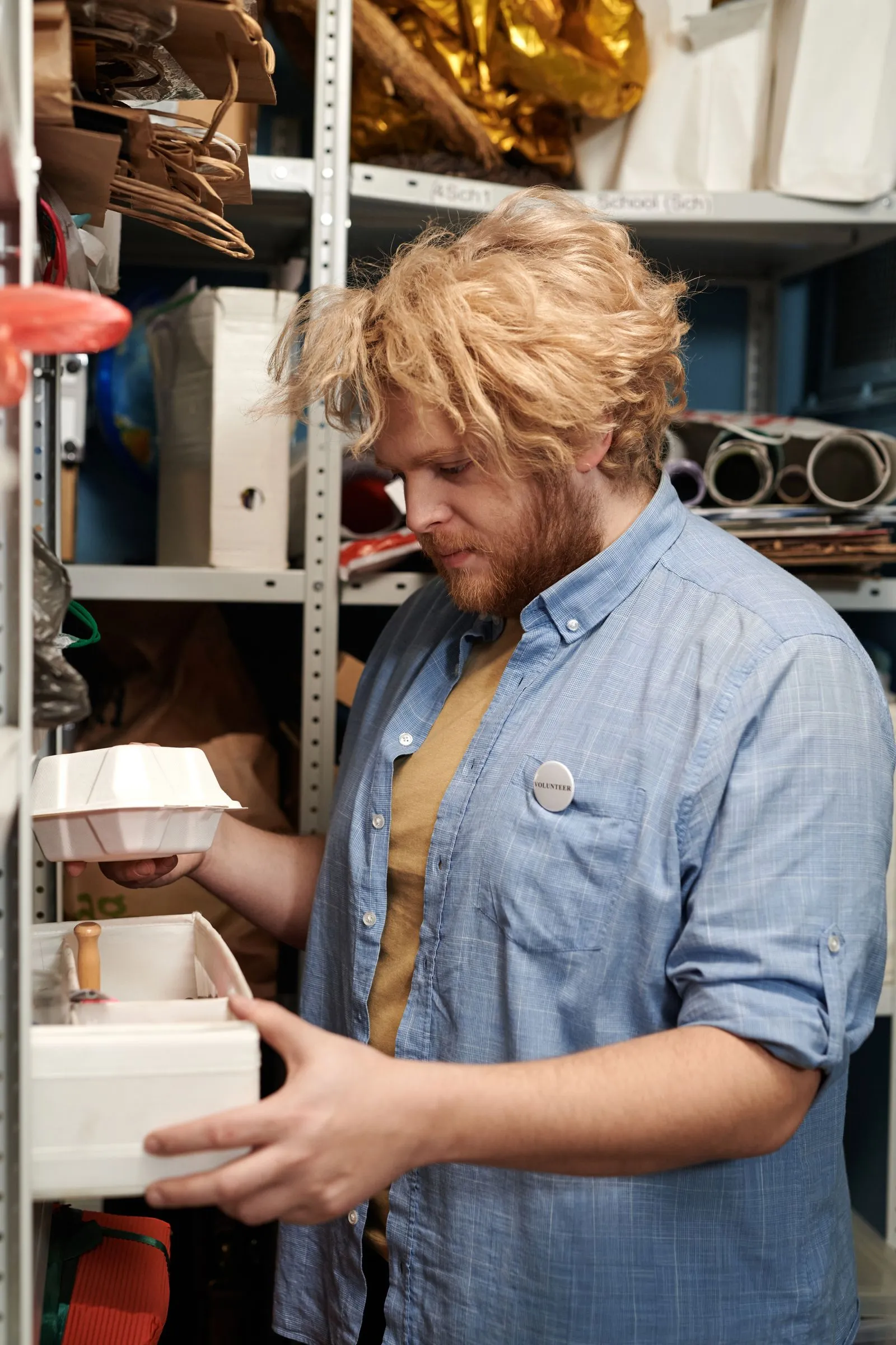 A man sorting boxes on shelves in a packed storeroom